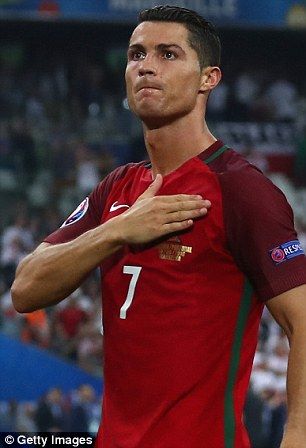 a man standing on top of a soccer field wearing a red shirt and green shorts