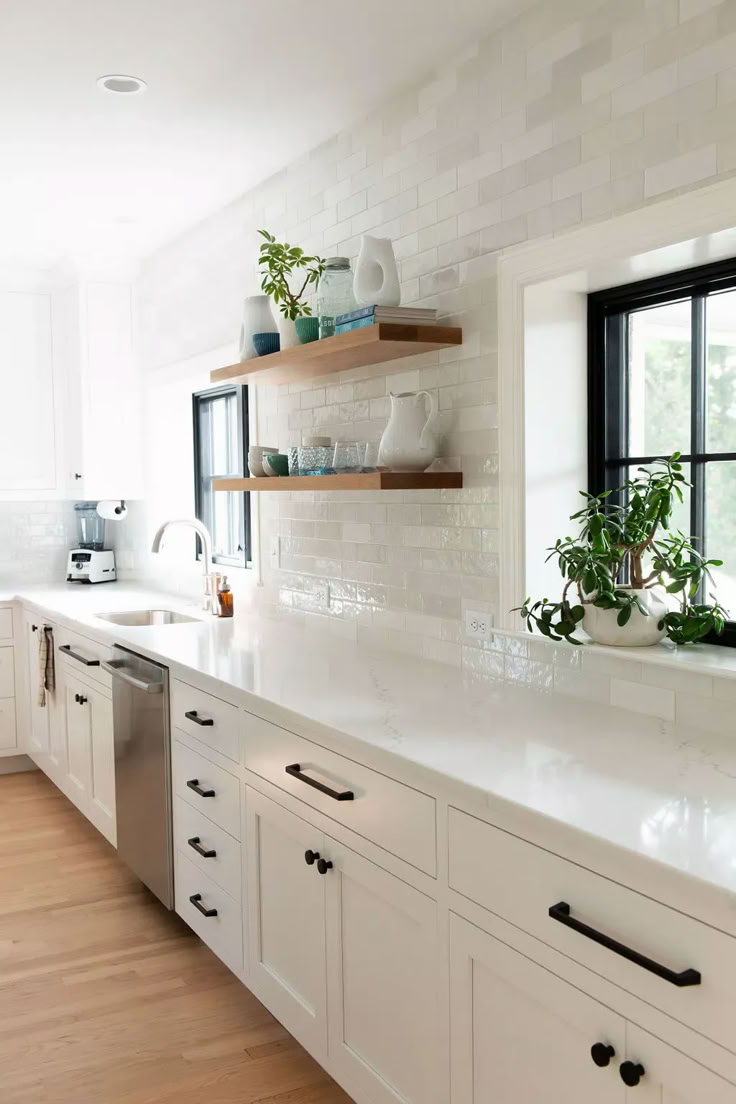 a kitchen with white cabinets and open shelving above the sink is seen in this image