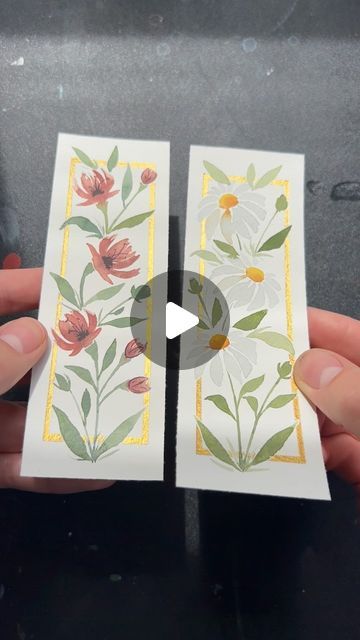 someone holding two cards with flowers on them