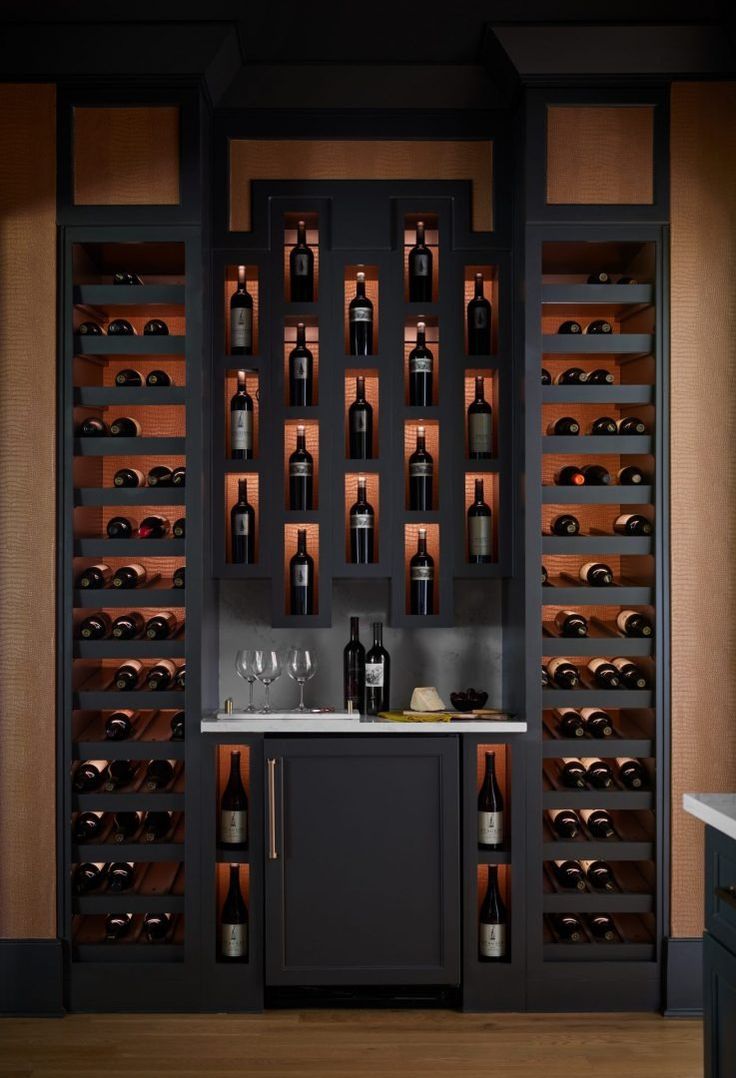 a wine cellar filled with lots of bottles and glasses on top of a counter next to a sink