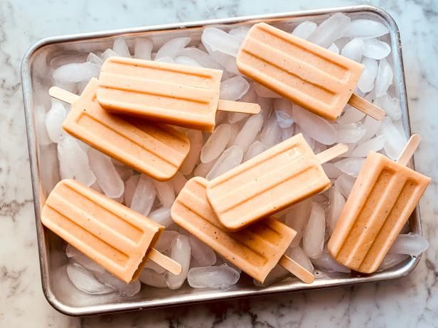 four popsicles sitting on top of ice in a metal tray