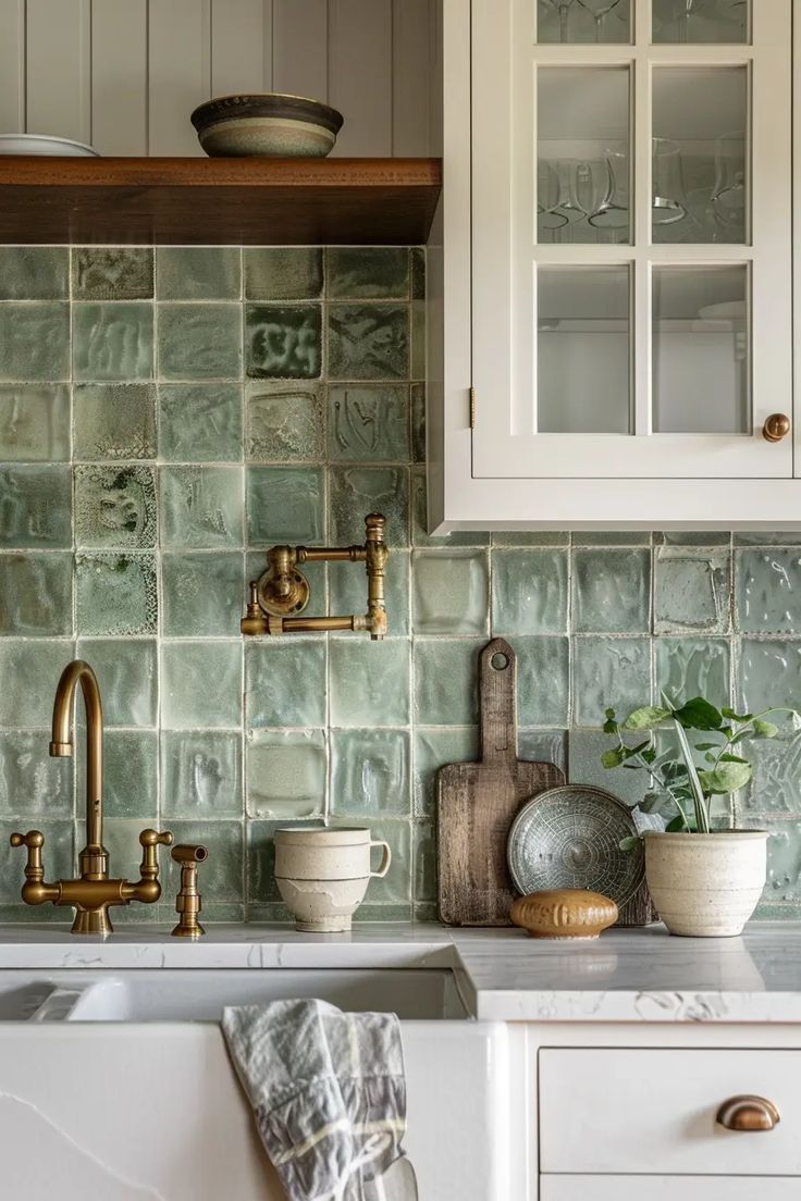 a kitchen with white cabinets and green tile backsplash, brass faucets