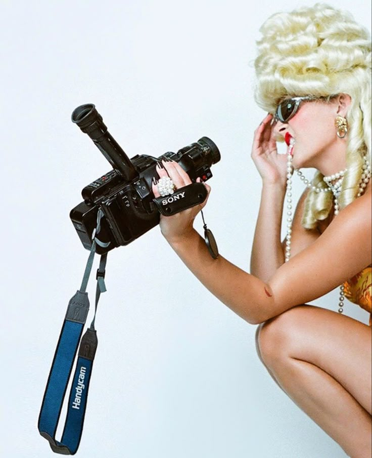 a woman with blonde hair and glasses holding a camera