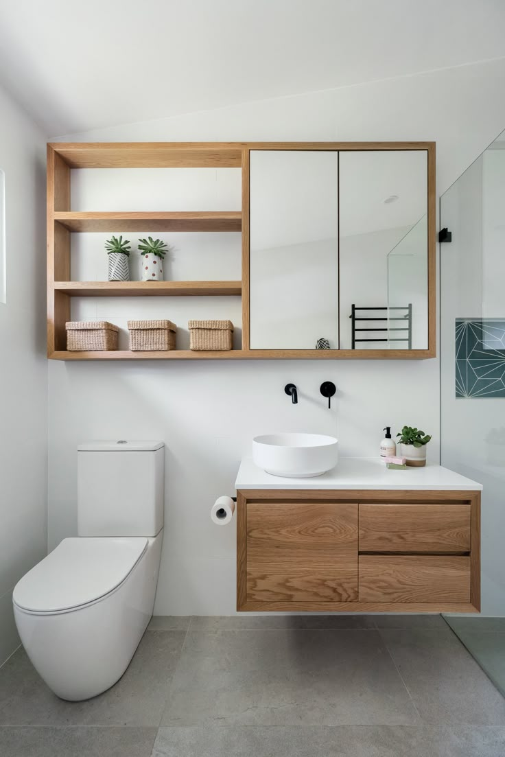 a bathroom with a toilet, sink and wooden cabinet in the corner on the wall