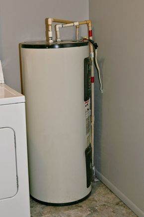 a water heater sitting next to a dryer in a room with a washer and dryer