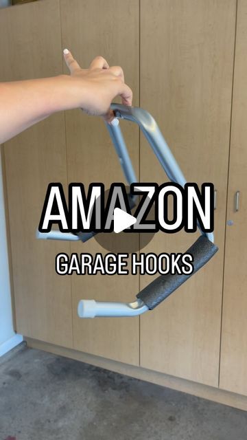 someone is holding onto the handle of an amazon garage hook in front of some cabinets