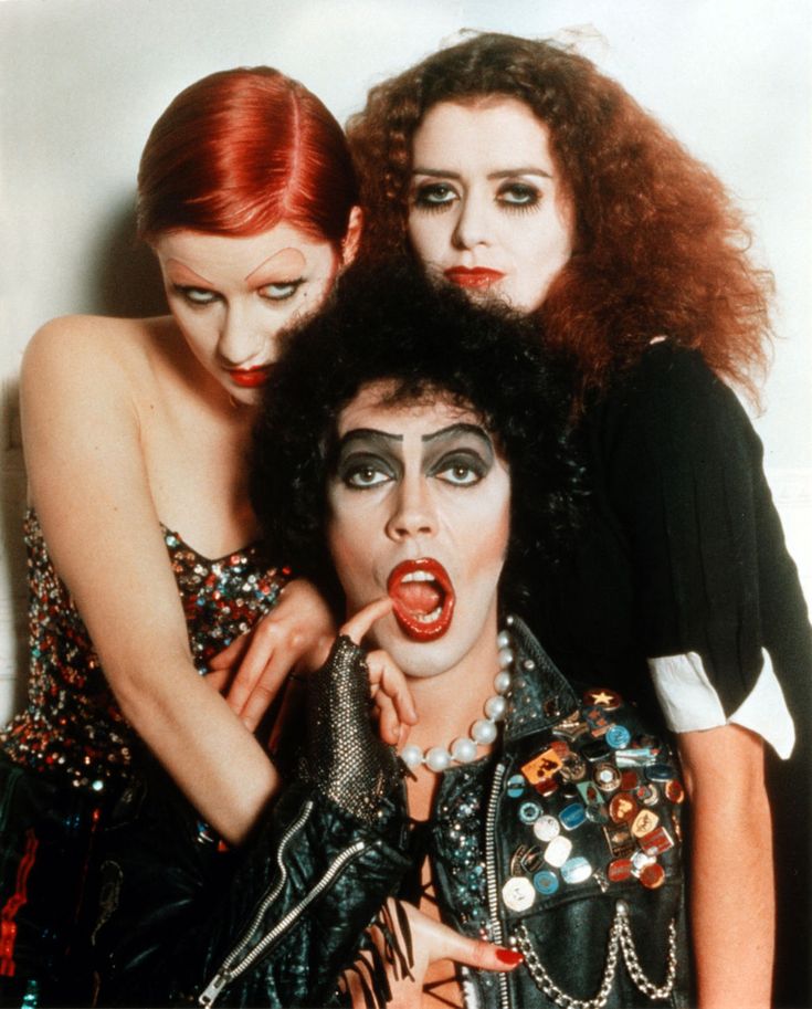 three women with makeup on their faces posing for the camera, and one woman has her mouth open