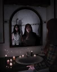 two women standing in front of a mirror with candles