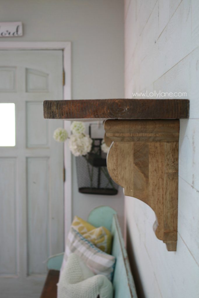 a wooden shelf with flowers on it next to a door