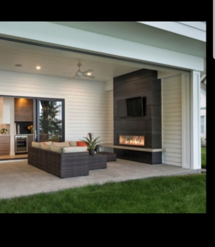 an outdoor living room with a fireplace and tv on the wall in front of it