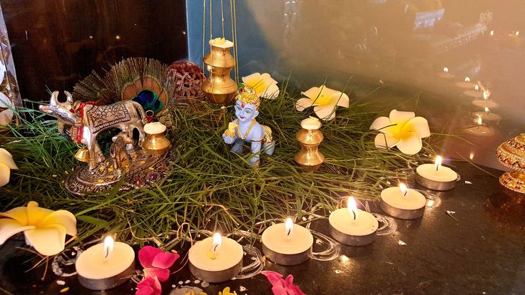 candles are placed on the ground in front of flowers and figurines that look like animals