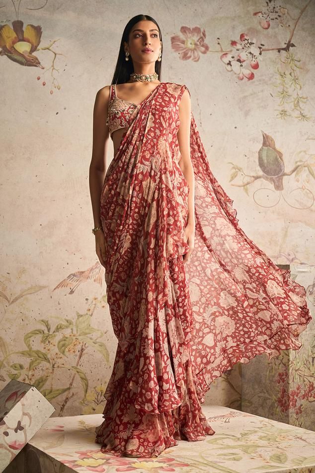 Red ochre pre-draped saree with all over floral print, pleated draped details, attached pallu and ruffle border. Paired with sweetheart neck printed blouse with all over 3D applique, beads, pearl, zari and sequin embroidery.
Components: 2
Pattern: Printed and Embroidered
Type Of Work: Floral Print, Pearl, Bead, Zari and Sequin Work
Neckline: Sweetheart Neck
Sleeve Type: Sleeveless
Fabric: Saree: Chiffon, Blouse: Net
Color: Red
Other Details: 
Beaded highlights
Occasion: Destination Wedding,Sange Graduation Saree, Printed Chiffon Blouse, Red Ochre, Ruffle Saree, Embroidered Crop Tops, Drape Saree, Indian Dresses Traditional, Saree Trends, Red Saree