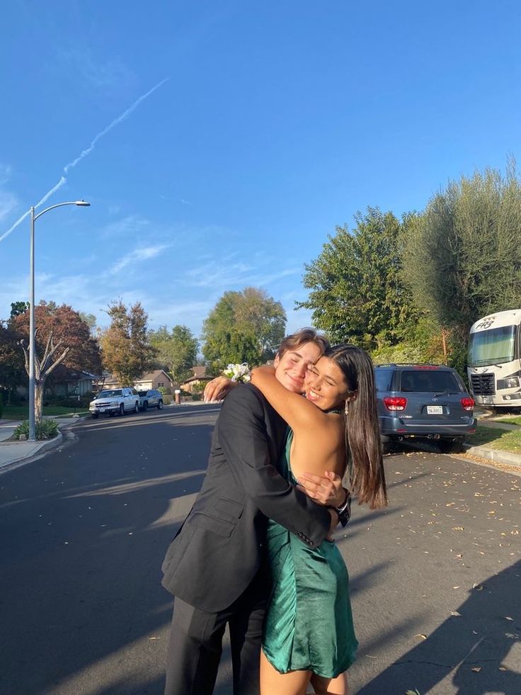 two people hugging each other on the street