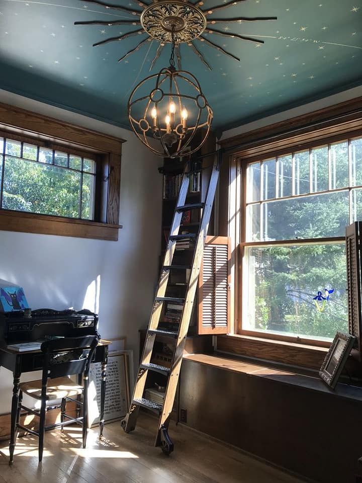 a living room filled with furniture and a chandelier hanging from the ceiling next to a window