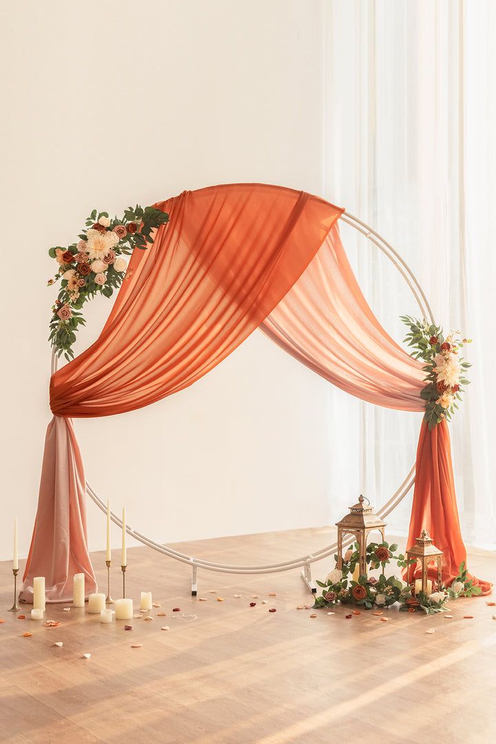 an orange drape draped over a wooden floor with candles and flowers on the side