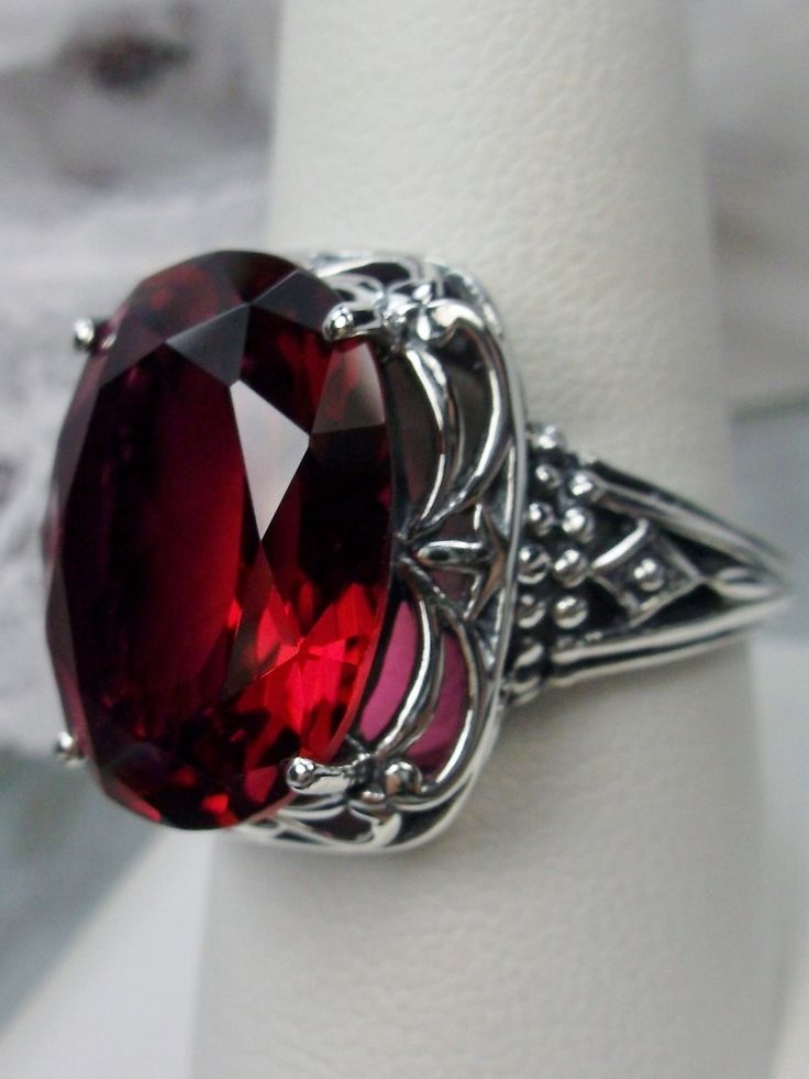 Art Deco Red Ruby Sterling Silver RingRetro Swirl Design#D119 Unlock the mysteries of the past and add a hint of vintage glamour to your jewelry wardrobe with Retro Swirl Ring. Constructed from 925 sterling silver, its intricate filigree swirls create an eye-catching Art Deco-inspired design – perfect for those looking to make a contemporary statement. Featuring a generously sized 18mm x 13mm Red Ruby gemstone in its prong setting, this ring sits 3/4" north south on your finger and 10mm off the Elegant Red Cabochon Ruby Ring, Elegant Large Stone Ruby Ring Gift, Elegant Ruby Ring With Large Stone For Gift, Antique Oval Red Ruby Ring, Victorian Red Oval Cabochon Jewelry, Victorian Oval Ruby Ring For Formal Occasions, Formal Oval Ruby Ring, Vintage Red Ruby Ring With Intricate Design, Oval Ruby Ring Collectible