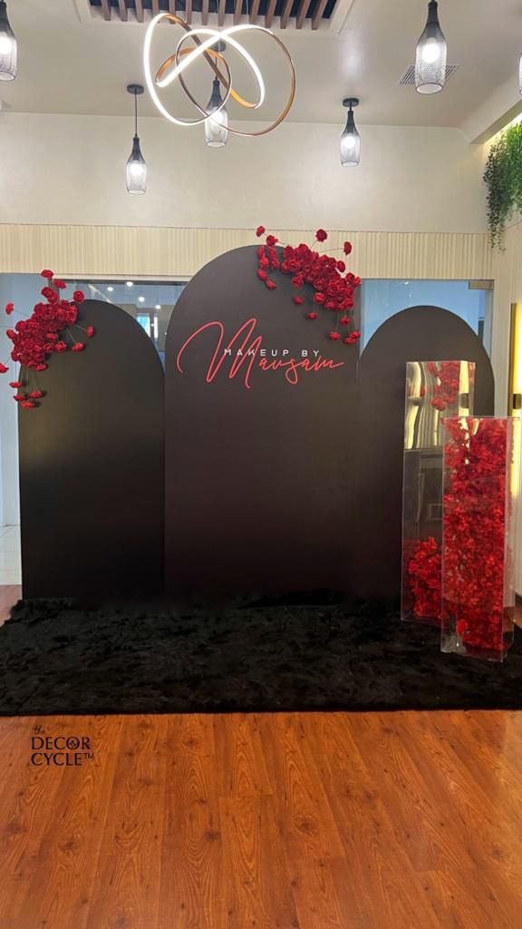 the entrance to an event with red flowers in vases and black carpet on the floor