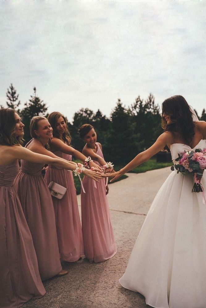 a group of bridesmaids holding hands and smiling at each other on the street