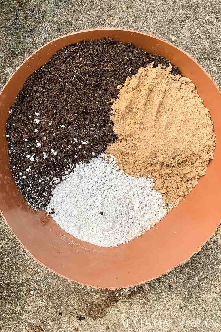 a brown bowl filled with different types of dirt and gravel next to a cement floor