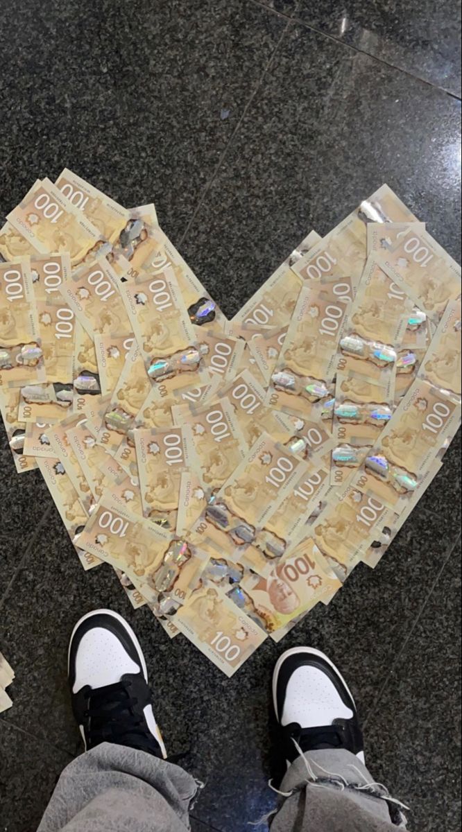 a person standing in front of a heart made out of money on top of a floor