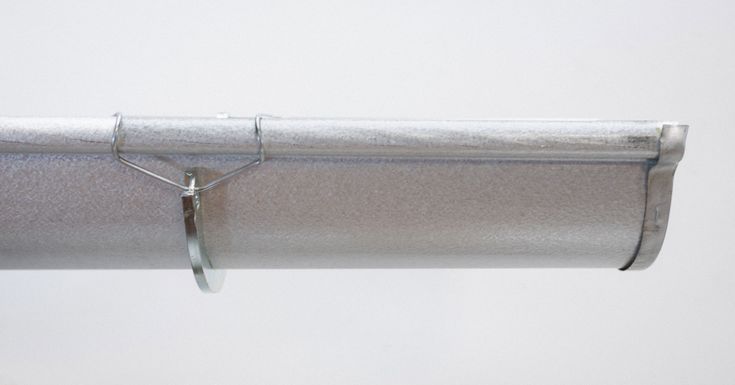 a close up of a metal pipe with a white wall in the backgroud