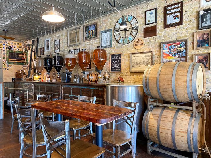 a room filled with lots of wine barrels and wooden tables in front of a brick wall