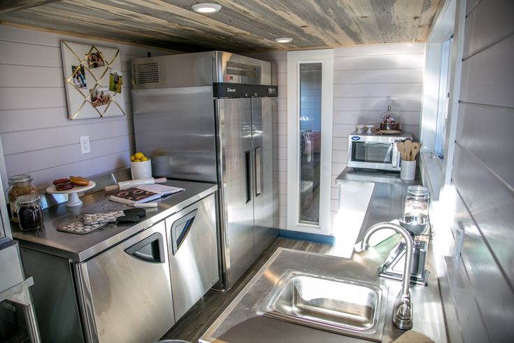 a kitchen area with stainless steel appliances and counter tops, along with wood plank ceilinging