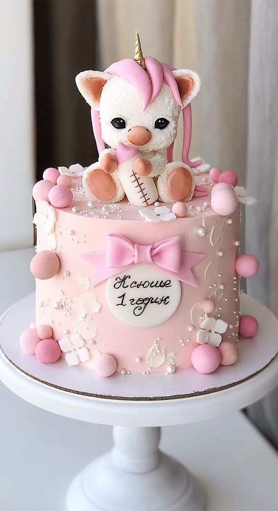 a pink and white cake with a stuffed animal on top