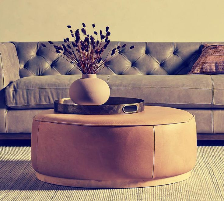 a living room with a couch, coffee table and vase on the floor in front of it