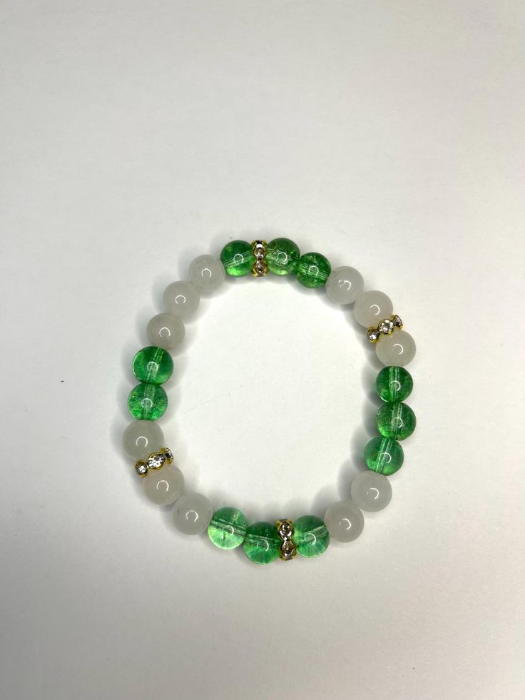 Green and off white handmade beaded bracelet with gold accents. Stylish accessory Cheap Nickel Free Green Bracelets, Cheap Green Beaded Bracelets, Cheap Green Beaded Friendship Bracelets, Cheap Green Bracelets For Holiday, Green Pearl Bracelet, White Stretch Bracelet With Gold Beads As Gift, White Spiritual Beaded Bracelets With Gold Beads, White Spiritual Beaded Bracelet With Gold Beads, Handmade White Jade Bracelets