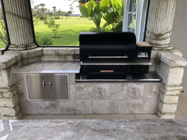 an outdoor bbq with grill and sink in front of a large window