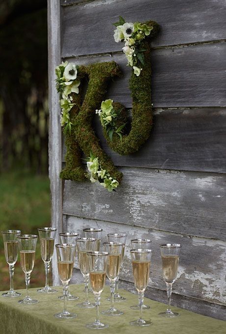 wine glasses are lined up in front of a wooden sign with the letter k on it