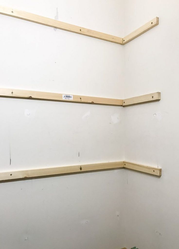 three wooden shelves in the corner of a room with no one around them on the floor