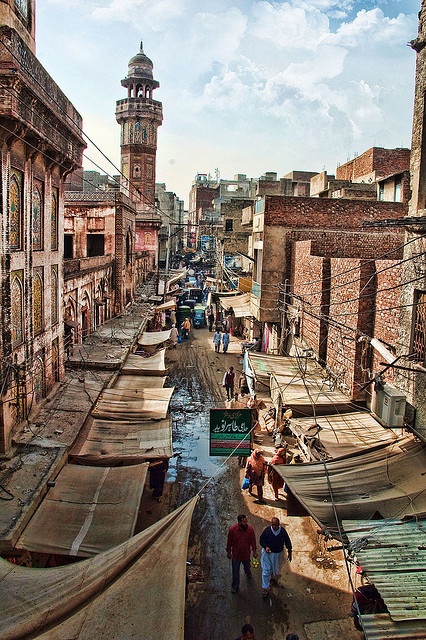 an old city street with people walking down it