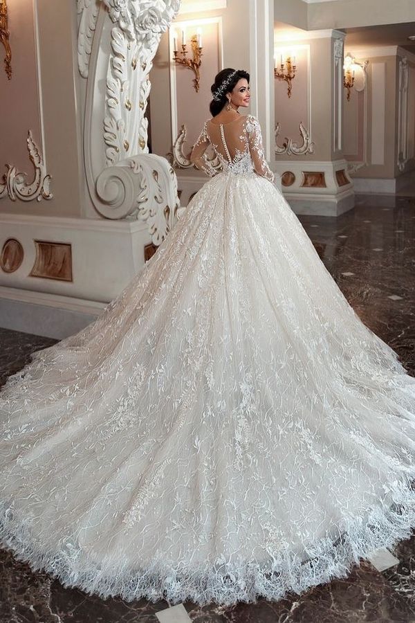 a woman in a wedding dress is standing near a wall and looking at the mirror