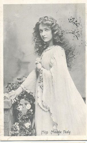 an old black and white photo of a woman wearing a dress with flowers on it