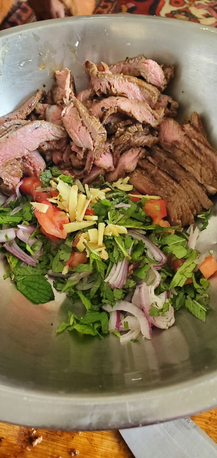 a bowl filled with meat and vegetables on top of a table