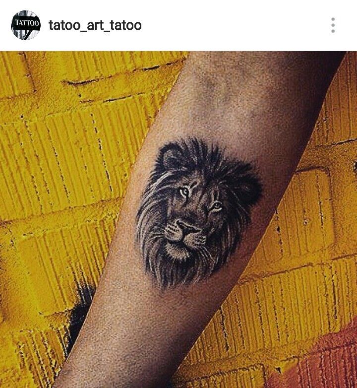 a lion tattoo on the right arm and leg, with an orange brick wall in the background