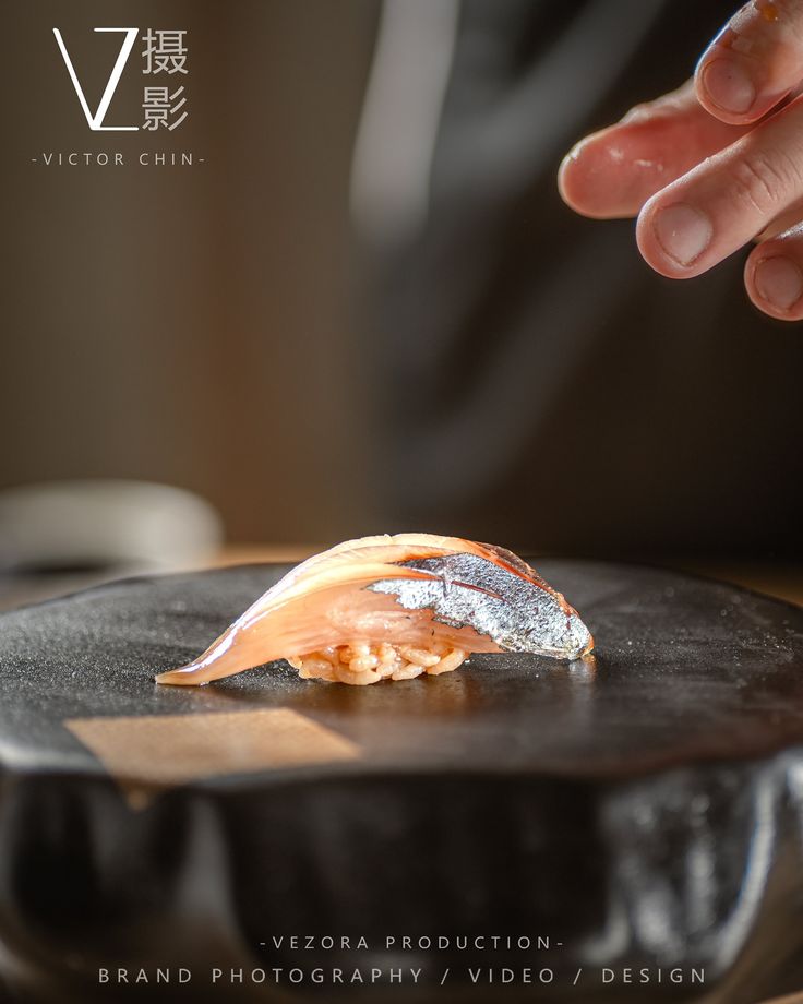 a person reaching for some food on top of a black plate in front of them