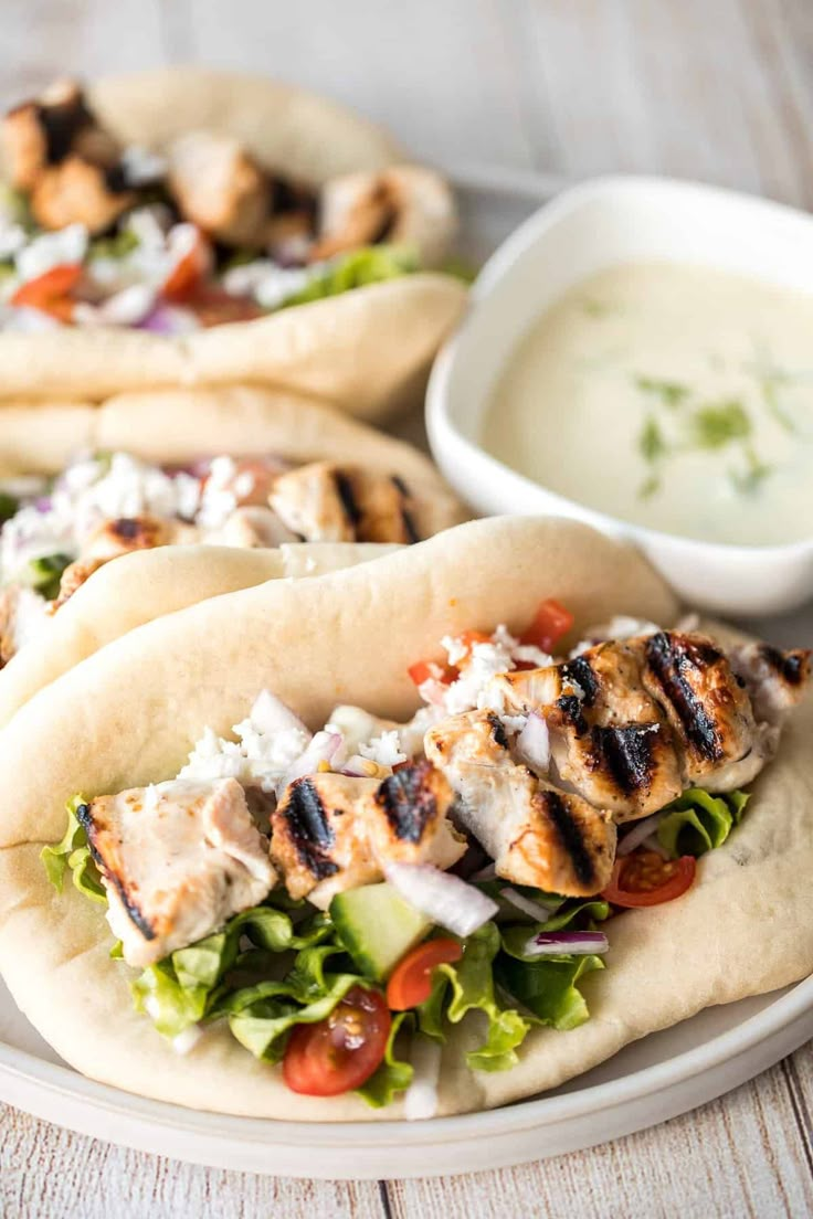 three pita breads with chicken, lettuce and tomato salad on them