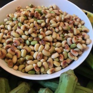 a white bowl filled with beans next to some green plantains on a black table