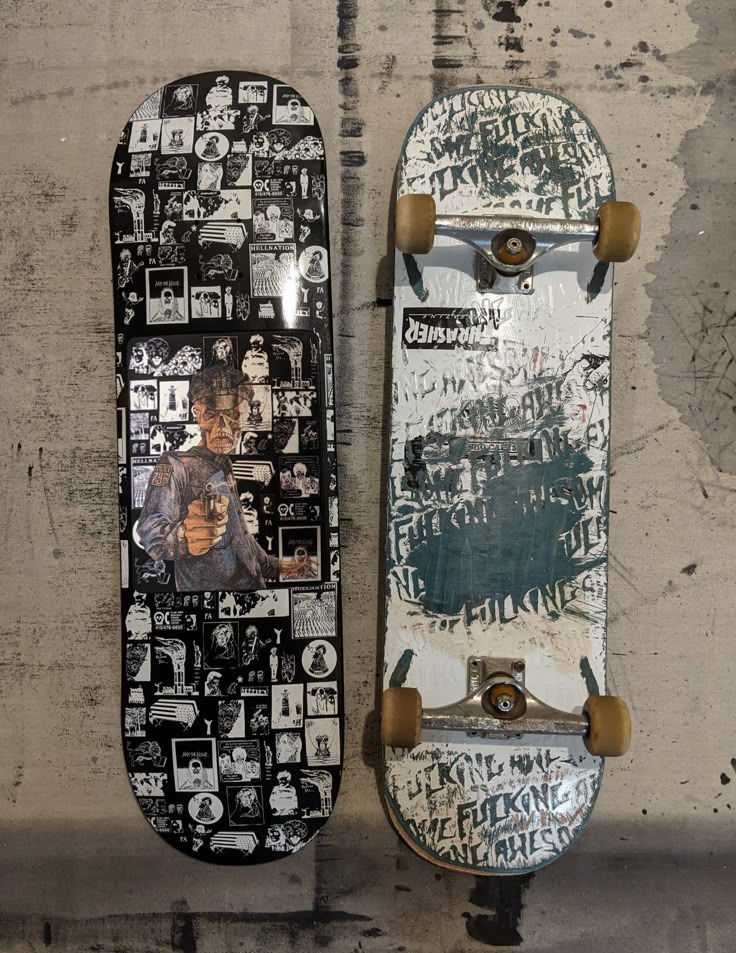 two skateboards sitting next to each other on a cement wall with stickers all over them