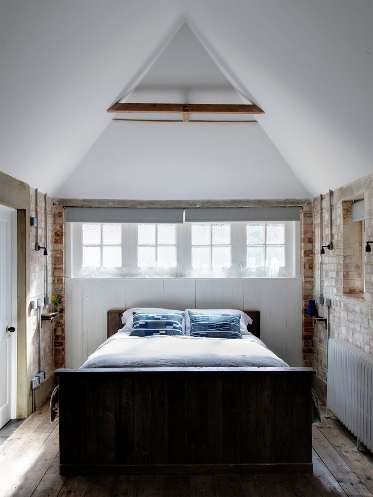 a large bed sitting in the middle of a bedroom under a slanted skylight