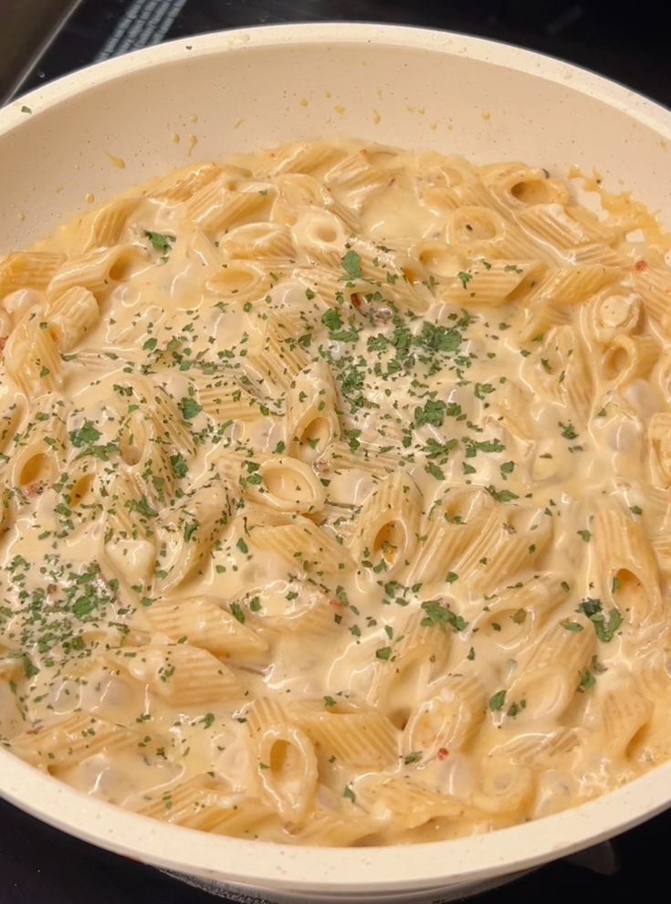 a white bowl filled with macaroni and cheese on top of a black stove