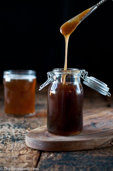 caramel syrup being poured into a glass jar on top of a wooden cutting board