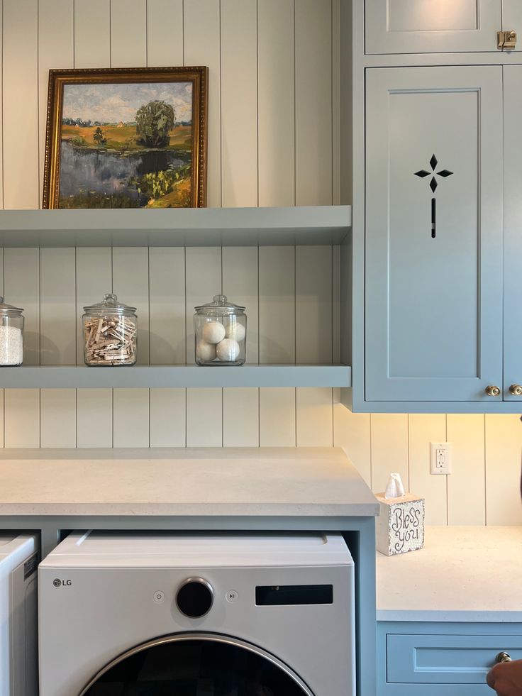 a washer and dryer in a room with blue cabinets on either side of the washer