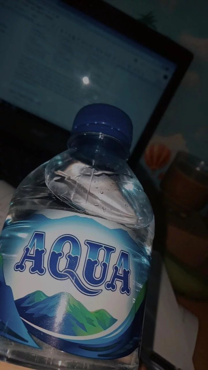 a bottle of water sitting in front of a laptop computer