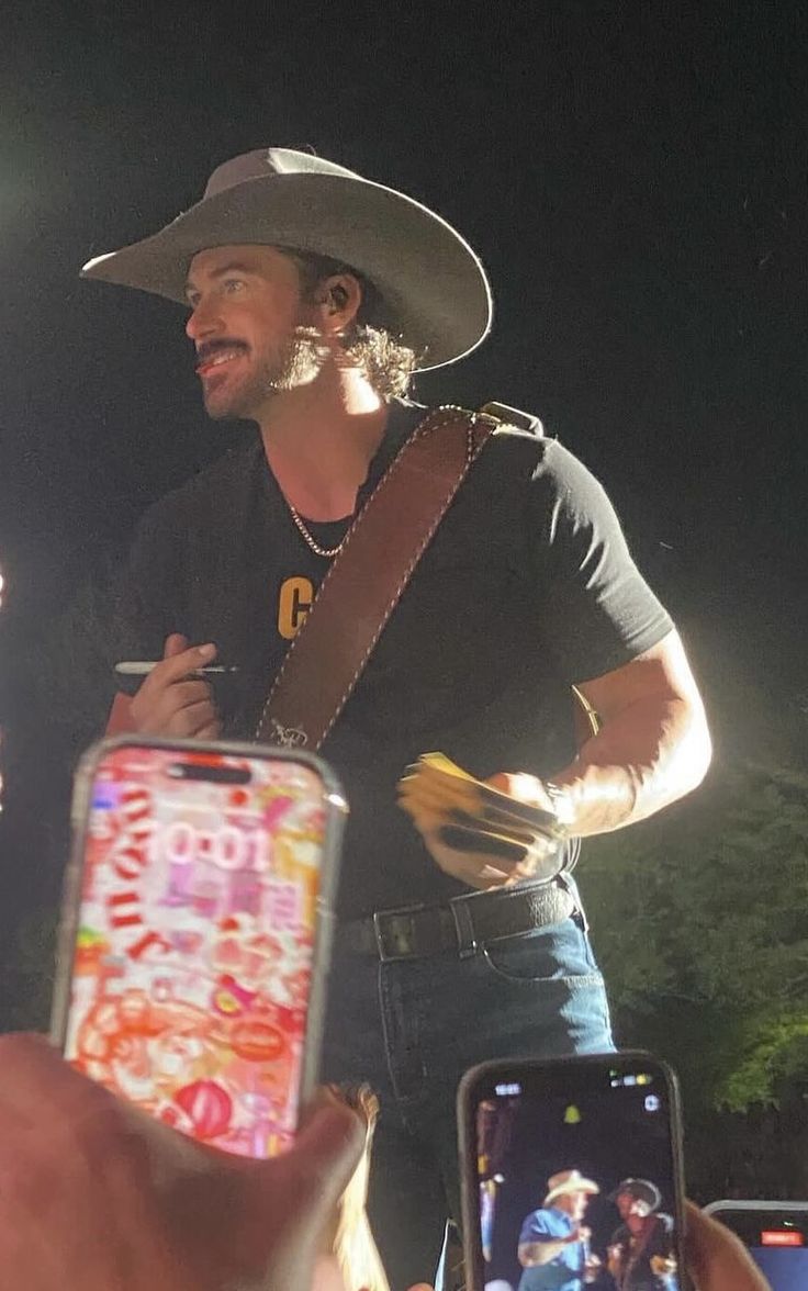 a man wearing a cowboy hat and holding a cell phone