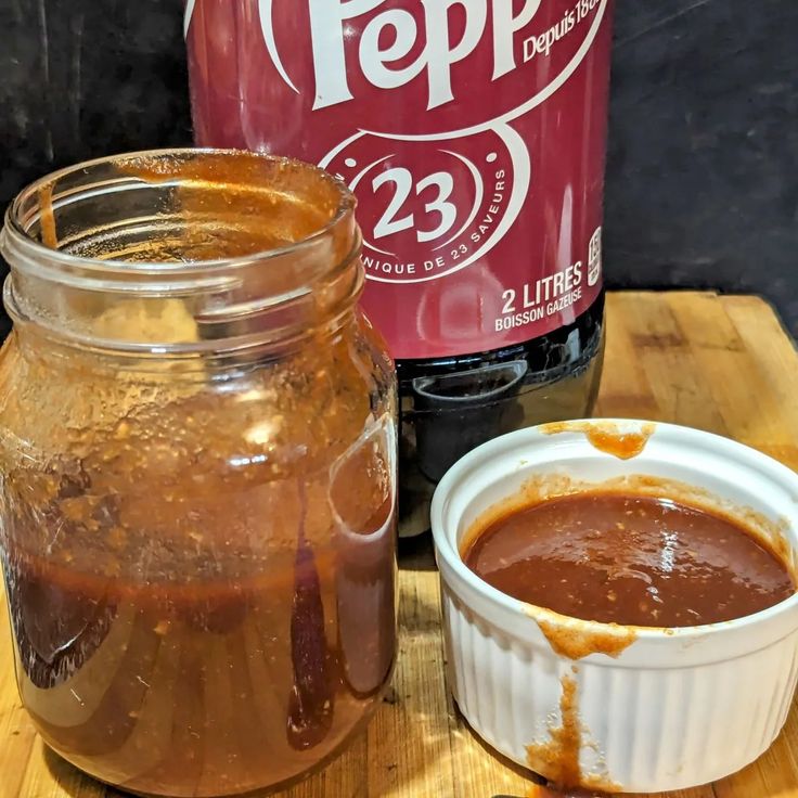 a jar of ice cream next to a container of hot sauce on a wooden table