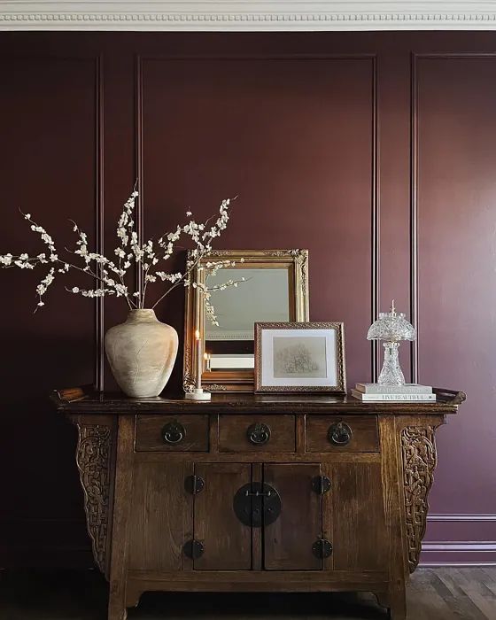 a wooden table topped with a vase filled with white flowers next to a mirror and framed photograph